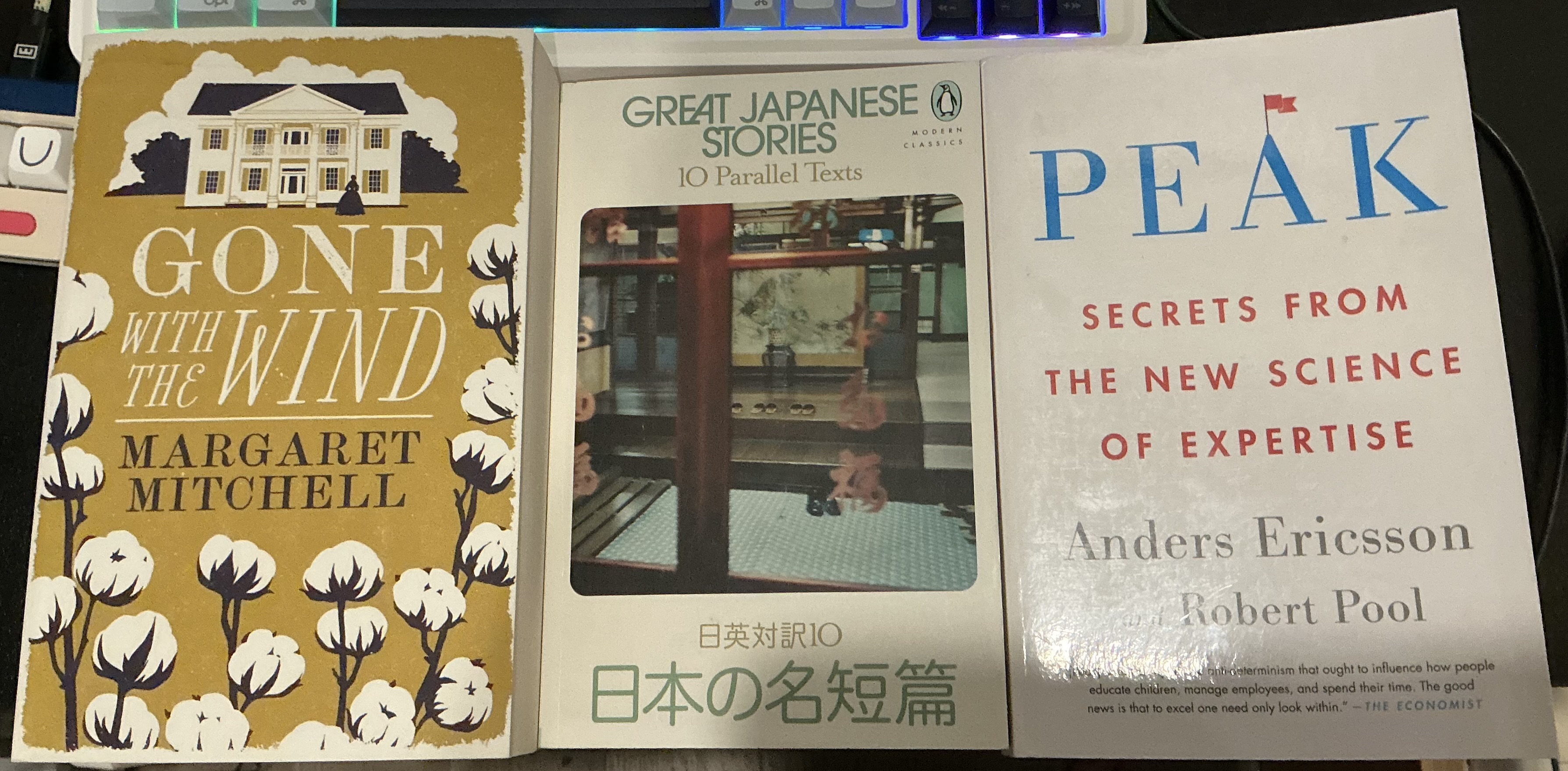 photo of 3 books laid side to side. from left to right: 'gone with the wind' by margaret mitchell, 'great japanese stories: 10 parallel texts' published by penguin books, 'peak: secrets from the new science of expertise' by anders ericsson and robert pool